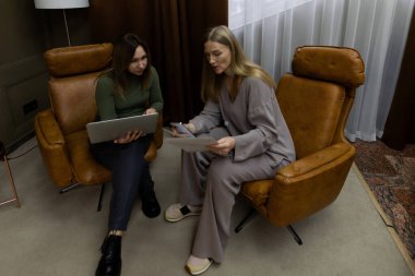 İki kadın, modern mobilyalarla çevrili sıcak ve cezbedici bir ev ortamında belgeleri incelerken verimli bir tartışmaya girişirler..