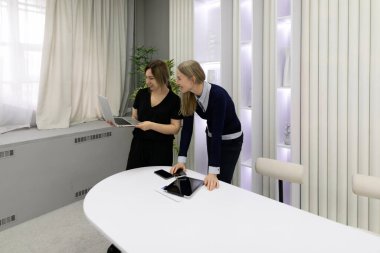 İki kadın laptoptaki belgeleri incelerken verimli bir tartışmaya giriştiler. Modern ofiste hafif ışıklandırma ve minimalist bir tasarım, işbirlikçi bir atmosfer yaratıyor..