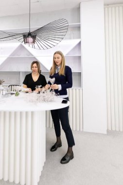 İki kadın, zarif bir çalışma alanında minimalist tasarım ve doğal ışık içeren süslemeler yapıyorlar. Malzemelerle çevrili yaratıcı görevlerine odaklanmışlar..