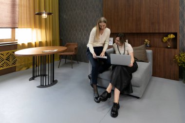 İki kadın kapalı bir alanda kooperatif bir proje yürütüyorlar. Bir kadın dizüstü bilgisayarla koltukta otururken, diğeri elinde tabletle oturmuş, fikirleri tartışıyor..