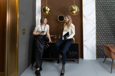 İki kadın bir ev dekorasyonu sergisinde çağdaş mobilyaların yanında dururken aynı fikirleri paylaşıyor..