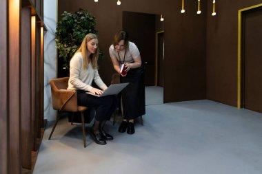 Şık dekorlu çağdaş bir ofiste, iki iş arkadaşı bir dizüstü bilgisayarla ilgili bir tartışmaya girişiyor, akşam erken saatlerde bir proje üzerinde çalışırken fikir ve içgörülerini paylaşıyorlar..