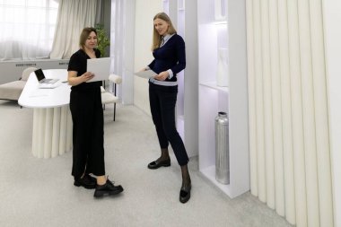 Çağdaş bir ofiste iki kadın profesyonel bir tartışmaya giriyorlar. Biri belgeleri incelerken diğeri dizüstü bilgisayarla oturur ve ışık dolu bir alanda fikirlere katkıda bulunur..