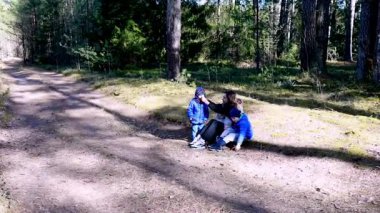 Huzurlu bir ormanda, üç çocuk, uzun ağaçlar ve yeşilliklerle çevrili sıcak güneşin altında kahkahalarını ve hikayelerini paylaşıyorlar..