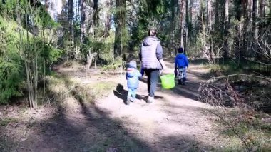 Aile güneşli bir orman yolunda yürüyor, çocuklar heyecan içinde etrafı keşfederken bir kovada eşyalar topluyor. Doğa onları barışçıl bir ortamda sarmış..