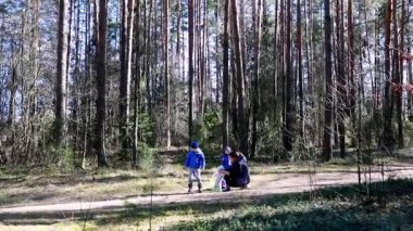 İki kişi bir orman yolu boyunca doğayı inceleyen bir açık hava aktivitesiyle meşgul. Yükselen ağaçlar ilginç öğeler topladıkça huzurlu bir atmosfer yaratıyor..