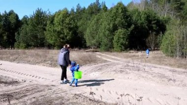 Aile üyeleri bir bahar günü güzel bir ormanı keşfederler. Kalın giysiler giyen bir çocuk, bir yetişkin yanında yürürken heyecanlı bir şekilde eşyalar topluyor..