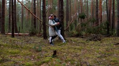 İki birey, uzun ağaçlar ve gür yeşilliklerle çevrili sakin bir ormanı keşfediyor. Kahkahaları paylaşıyorlar ve dışarıda birbirlerine eşlik ederek eğleniyorlar..