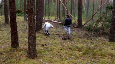 Bir grup aile, serin bir öğleden sonra serin bir ormanda düşmüş dalları ve yakacak odunlarını toplayarak açık havada bir etkinliğe girişiyor. Aynı gülüşü paylaşıyorlar ve doğanın güzelliğinden zevk alıyorlar..