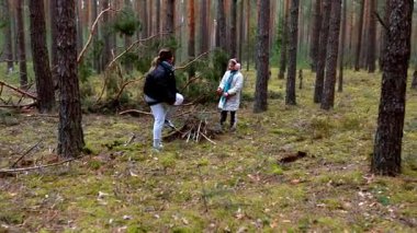 Sakin bir ormanda, iki kişi odun ve odun toplamakla meşgul. Kamp ateşi için gerekli malzemeleri toplamak için birlikte çalışıyorlar..