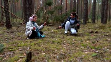İki arkadaş ağaçlarla çevrili orman zemininde oturur, müzik aletleri çalar ve öğleden sonraları sakin bir açık havada kahkahalarını paylaşırlar..