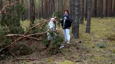 Sakin bir ormanda, iki birey açık havada eğlenirken düşmüş dallarla çarpışır. Takım çalışmasını, yüksek ağaçlarla çevrili doğal bir ortamda gösteriyorlar..