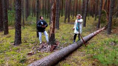 İki arkadaş yemyeşil bir ormanda, devrilmiş ağaçların ve yeşilliklerin arasında gezinerek eğleniyorlar. Gülüyorlar ve hareketli bir atmosferde huzurlu bir çevreyle iç içe geçiyorlar..