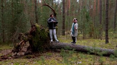 Bereketli bir ormanda, iki arkadaş açık havada, büyük, devrilmiş bir ağaç gövdesinde dengeli ve uzun, yeşil ağaçlarla çevrili olarak vakit geçirmeyi severler. Huzurlu atmosfer onların neşeli keşiflerini vurguluyor..