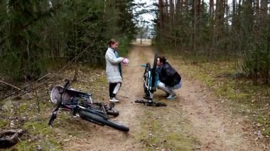 İki kişi bir bisiklet tamir ederken orman yolunda mola veriyor. Bir kişi kaskını tutar ve sohbet eder, diğeri ise dışarıda sakin bir günde bisiklet lastikleriyle uğraşır..