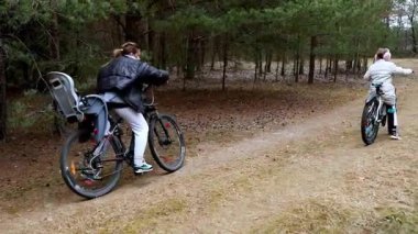 İki birey, huzurlu bir orman patikası boyunca dönerler. Bir bisikletin, huzurlu bir ortamda birlikte doğayı keşfederken eğlence için çocuk koltuğu vardır..