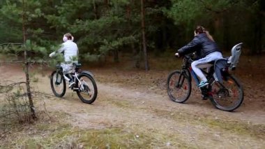 İki birey ağaçlarla çevrili manzaralı bir orman yolunda bisiklet macerasından zevk alıyor. Sürücülerden biri diğerini yakından takip ederken, boş zamanlarında aile bağlarını gözler önüne seriyor..