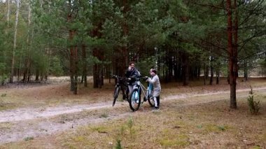 Bir ebeveyn ve çocuk huzurlu bir ormanda bisiklet sürmeye ara verir. Etrafları ağaçlarla çevrili, serin bir sonbahar gününde doğanın güzelliğinin tadını çıkarırlar..