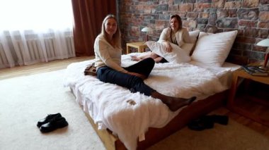 İki kadın, rahat bir odada taştan duvarlar olan lüks bir yatakta oturuyor. Güneş ışığı pencereden akar ve sıcak ve davetkar bir ortam yaratır..