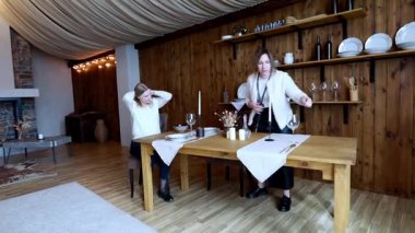 İki arkadaş kırsal kesimde sıcak bir yemek masası hazırlıyorlar. Tabak ve bardakları düzenliyorlar. Birlikte yemek yemeye hazırlanırken hoş bir ortam yaratıyorlar..