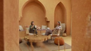 İki arkadaş, Fas 'tan esinlenilmiş tasarımlar ve zengin renklerle bezenmiş sıcak ve davetkâr bir yerde sohbet etmekten hoşlanırlar. Atmosfer rahatlatıcı ve canlı..