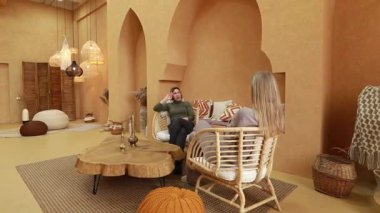 İki birey, şık ve rahat bir mekanda dostça bir sohbete girişir. İç kısımda sıcak tonlar ve doğal malzemeler var, rahat bir atmosfer yaratıyorlar..