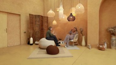 Rahat bir atmosfer, iki arkadaşın şık dekorlarla çevrili anlamlı bir sohbete girmesiyle oluşur. Yumuşak ışıklandırma ve rahat oturma, sıcak havayı arttırır..