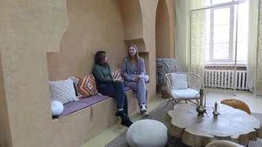 İki arkadaş, yumuşak dokular ve çağdaş tasarımlarla dolu rahat ve şık bir yaşam alanında oturuyorlar. Davetkar bir atmosfer içinde canlı bir sohbete dalarlar..