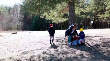 Aileler, çocukların toprağı keşfettiği ve yetişkinlerin etkinliklere hazırlandığı güneşli bir günün tadını çıkarıyorlar. Atmosfer canlı ve heyecanla dolu..