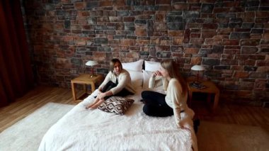 İki genç kadın sıcak bir yatak odasında yumuşak bir yatakta otururken canlı bir sohbete dalıyorlar. Kırsal taş duvar rahatlatıcı atmosfere cazibe katıyor..