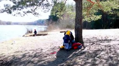 İki çocuk, güneşli bir bahar gününde sakin bir gölün kenarında neşeli bir anın tadını çıkarıyor. Bir çocuk ağacın altında dinlenirken diğeri yakınlardaki bölgeyi keşfediyor..