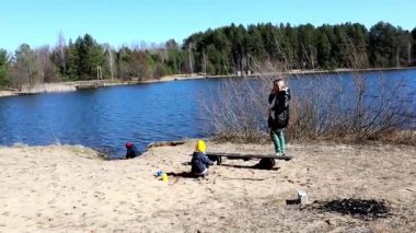 Bir aile sakin göl kenarında keyifli bir öğleden sonra geçirir, kumlu sahilde eğlenceli aktivitelerle meşgul olurken doğal çevreyi keşfeder..