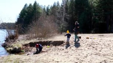 Bir aile güneşli bir bahar gününü gölde geçirir, açık hava aktiviteleriyle meşgul olurlar. Yetişkinler yakınlarda toplanıp huzurlu ortamın tadını çıkarırken çocuklar kumda oynuyor..