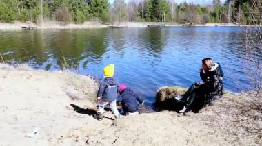 İki genç çocuk deniz kenarında oynayarak taşları topluyor ve doğayı keşfediyor. Bir yetişkin ise ağaçlarla çevrili huzurlu bir göl kenarında dinleniyor..