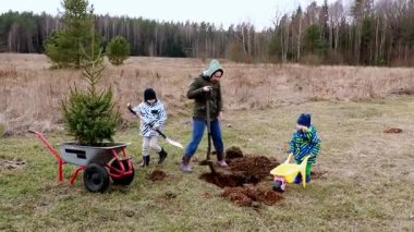Açık bir alanda, bir anne çukur kazarken çocuğu neşeyle küçük bir el arabasıyla yardımcı oluyor. Birlikte, genç bir ağaç dikiyorlar, doğayla bir bağ kuruyorlar..
