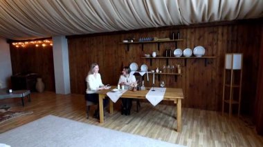 İki birey, ahşap bir odada samimi bir akşam yemeğini paylaşıyor ve anlamlı bir sohbete girişiyor. Zarif ayar güzel düzenlenmiş bir masa içeriyor..