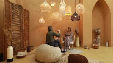 İki birey, sıcak ışık, doğal dokular ve eşsiz dekoratif elementlerle dolu güzel tasarlanmış bir iç mekanda derin bir sohbete girişerek rahatlatıcı bir atmosfer yaratırlar..