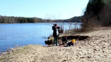 Çocuklar kumda oynarken bir aile göl kenarında kuşları ve doğayı gözlemleyerek kaliteli zaman geçirir. Bahar gününün sakinliği onların açık hava maceralarını arttırır..
