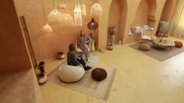 İki birey, benzersiz el yapımı dekorlarla dolu sıcak tonlu bir alanda düşünceli bir sohbete girişiyor. Sakinleştirici atmosfer huzur ve bağlantı hissini arttırır..