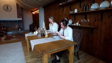 İki arkadaş, sıcak ışıklandırma ve zarif sofra düzenleriyle süslenmiş kırsal bir alanda, aşçılık deneyimleri için rahat bir ortam yaratarak samimi bir akşam yemeği toplantısı düzenliyor..