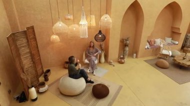 İki kadın güzel tasarlanmış bir salonda düşünceli bir tartışmaya giriyorlar. Sıcak renkler, şık dekorlar ve rahat koltuklar..