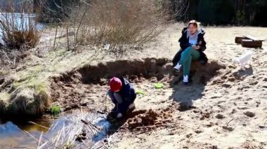Çocuklar göletin kenarında oyun oynuyorlar, çamurdan kale yapıyorlar ve sıcak güneşin tadını çıkarıyorlar. Kahkahalar havayı doldurur. Etraflarını keşfederler ve sakin bir öğleden sonranın tadını çıkarırlar..