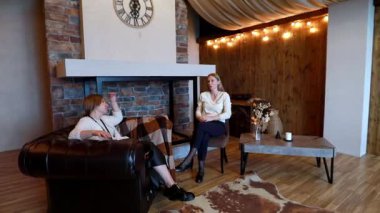 İki arkadaş, sıcak ışıklandırma ve kırsal bir ortam içeren rahat bir dinlenme odasında rahat bir sohbetin tadını çıkarıyorlar. Atmosfer davetkar, sosyalleşmek için mükemmel..