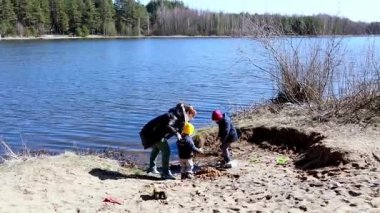 İki genç çocuk sakin bir nehir kıyısında kumu kazmaktan zevk alırken bir yetişkin onları izliyor. Parlak güneşli gün, onları çevreleyen bahar doğasının güzelliğini gözler önüne seriyor..