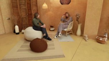 Sıcak, davetkar bir stüdyoda, iki kadın çeşitli konular hakkında bir animasyon tartışmasını paylaşıyor. Mekan, rahat atmosferi artıran basit mobilya ve toprak tonlarını içeriyor..