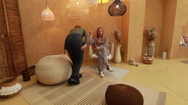 Dekorlu ve zarif döşemelerle dolu şık ve sakin bir atmosfer keşfedin. Bu davetkar, sıcak tonlu ortamda yaratıcılığı ön plana çıkaran iki birey etkileşim halindedir..