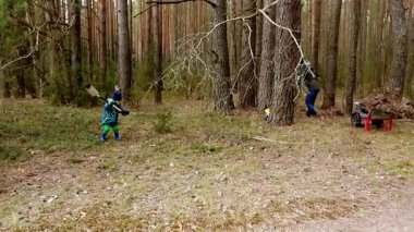 Sessiz bir orman bölgesinde, iki yetişkin toprağı ekim için hazırlarken bir çocuk toprağı kazıyor. Güneş ağaçların arasından süzülüp huzurlu bir atmosfer yaratıyor..