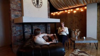 Rahat bir atmosferde, iki kadın rahat bir koltukta otururken samimi bir konuşma yaparlar. Sıcak ışıklandırma ve kırsal tasarım davetkar havayı arttırır..