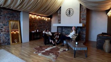 İki arkadaş güzel dekore edilmiş bir oturma odasında rahat koltuklarda rahatlar. Uzay, yumuşak ışık, doğal dokular ve hoş bir atmosfer yayar..