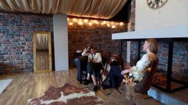 Bir grup arkadaş, taştan duvarlar ve sıcak ışıklandırmayla şık bir kamarada rahatlatıcı bir anın tadını çıkarıyor. Rahat bir oturma alanının yakınında gülüp sohbet ediyorlar..